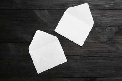 White paper envelopes on black wooden background, flat lay