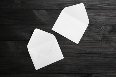 Photo of White paper envelopes on black wooden background, flat lay