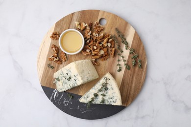 Tasty blue cheese with thyme, honey and walnuts on white marble table, top view