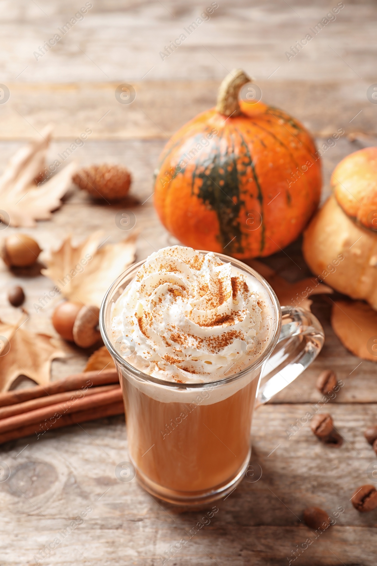 Photo of Glass cup with tasty pumpkin spice latte on wooden table