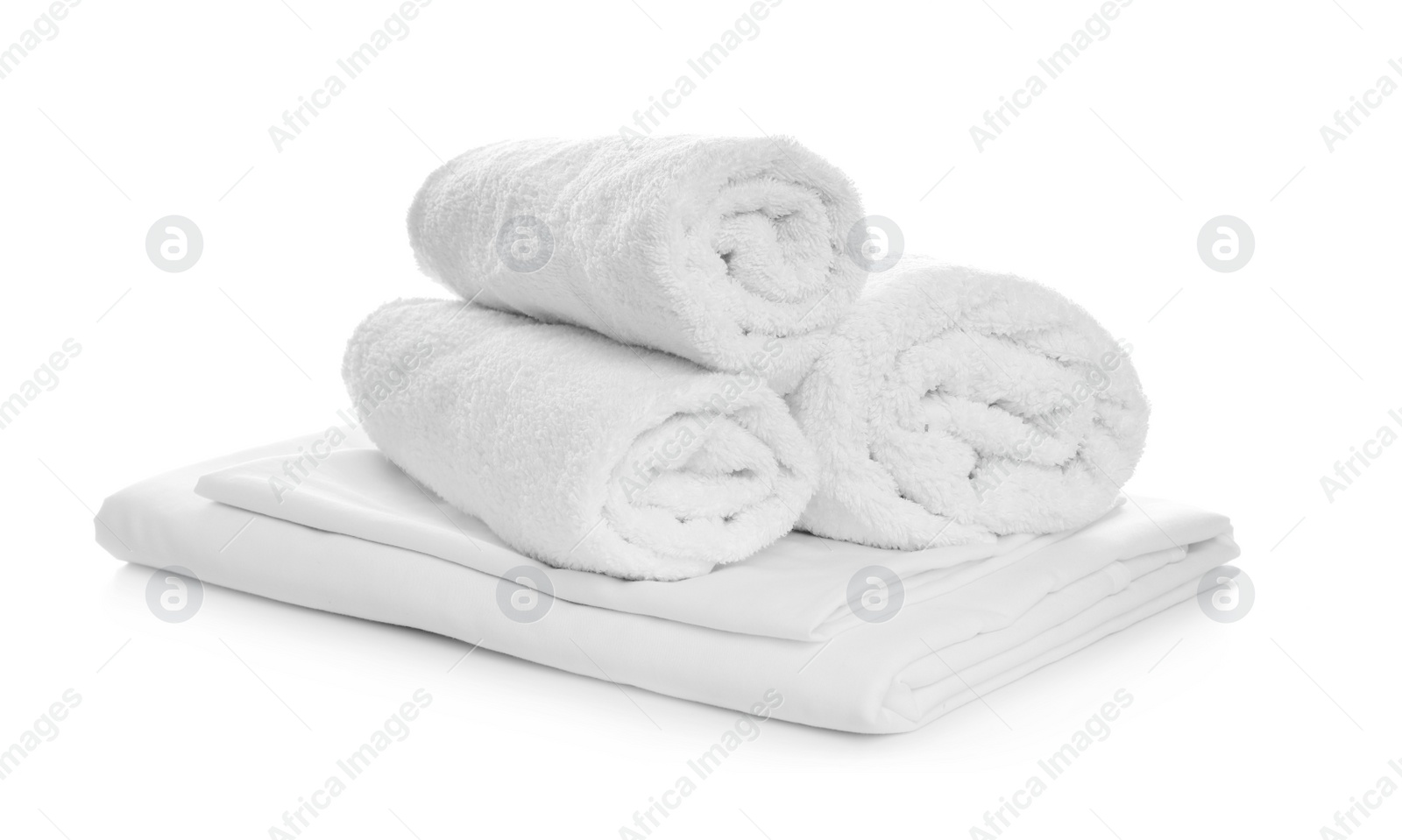 Photo of Rolled towels and folded bedding on white background