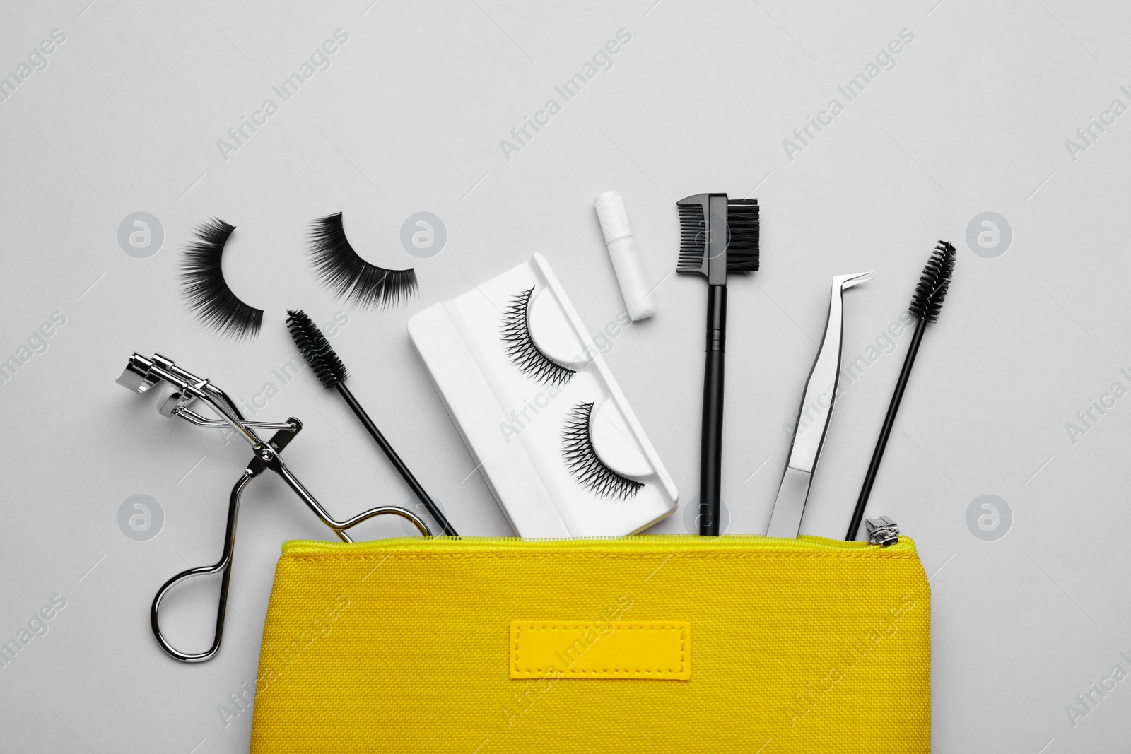 Photo of Flat lay composition with fake eyelashes, brushes and tools on light grey background