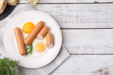 Photo of Delicious boiled sausages and fried eggs served on wooden table, flat lay. Space for text