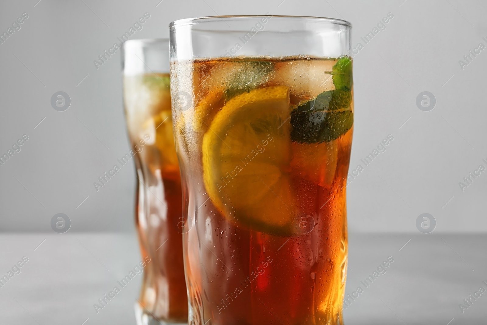 Photo of Glasses of refreshing iced tea against grey background, closeup