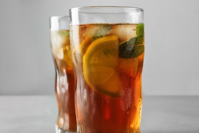 Glasses of refreshing iced tea against grey background, closeup