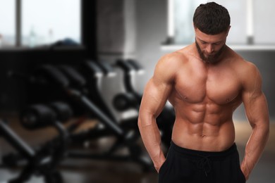 Handsome bodybuilder with muscular body in gym, space for text