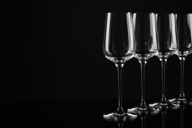 Photo of Set of empty wine glasses on black background. Space for text
