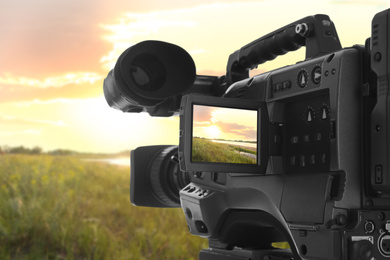 Image of Recording beautiful sunset on professional video camera