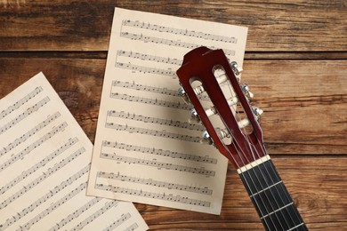 Composition with guitar and music notations on wooden table, flat lay