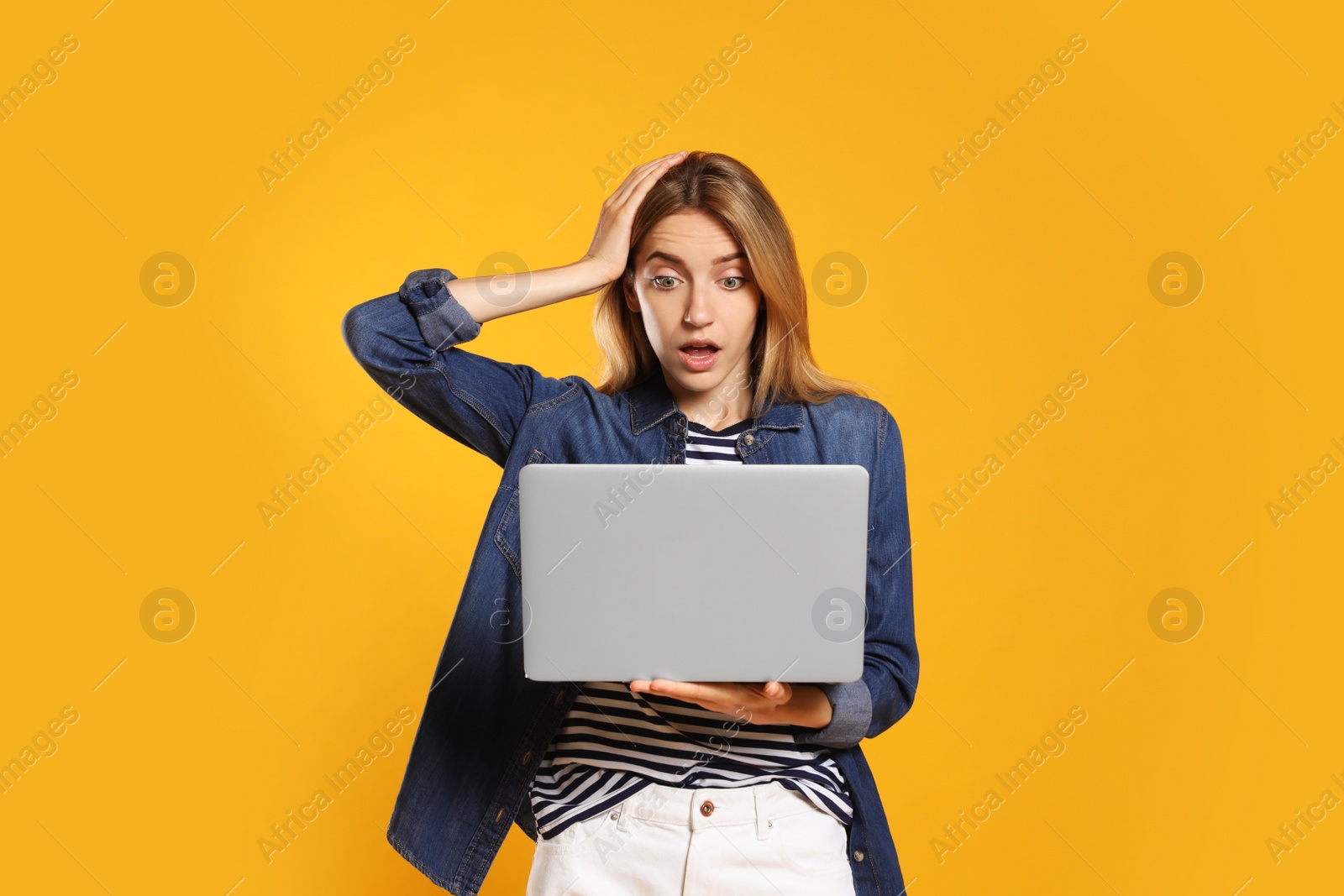 Photo of Portrait of emotional woman with modern laptop on yellow background