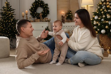Happy couple with cute baby in room decorated for Christmas