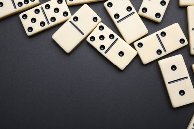 Photo of Classic domino tiles on black background, flat lay. Space for text