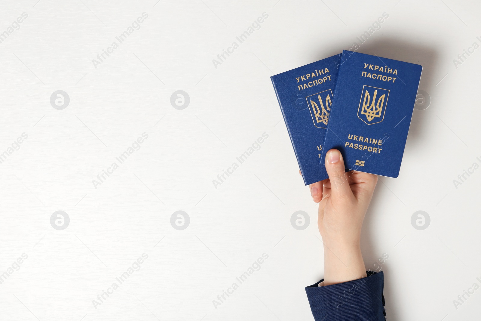 Photo of Woman holding Ukrainian travel passports on light background, top view with space for text. International relationships