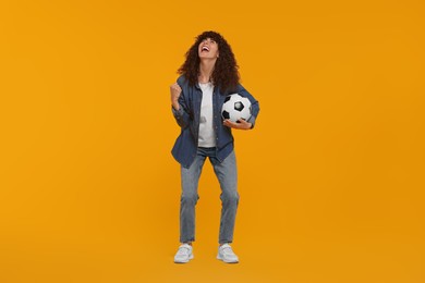 Photo of Happy fan with soccer ball celebrating on yellow background