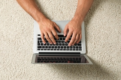 Man using laptop for search on floor, top view