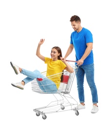 Young couple with shopping cart on white background