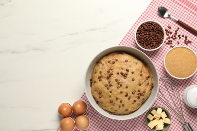 Bowl with dough and ingredients for cooking chocolate chip cookies on white marble table, flat lay. Space for text