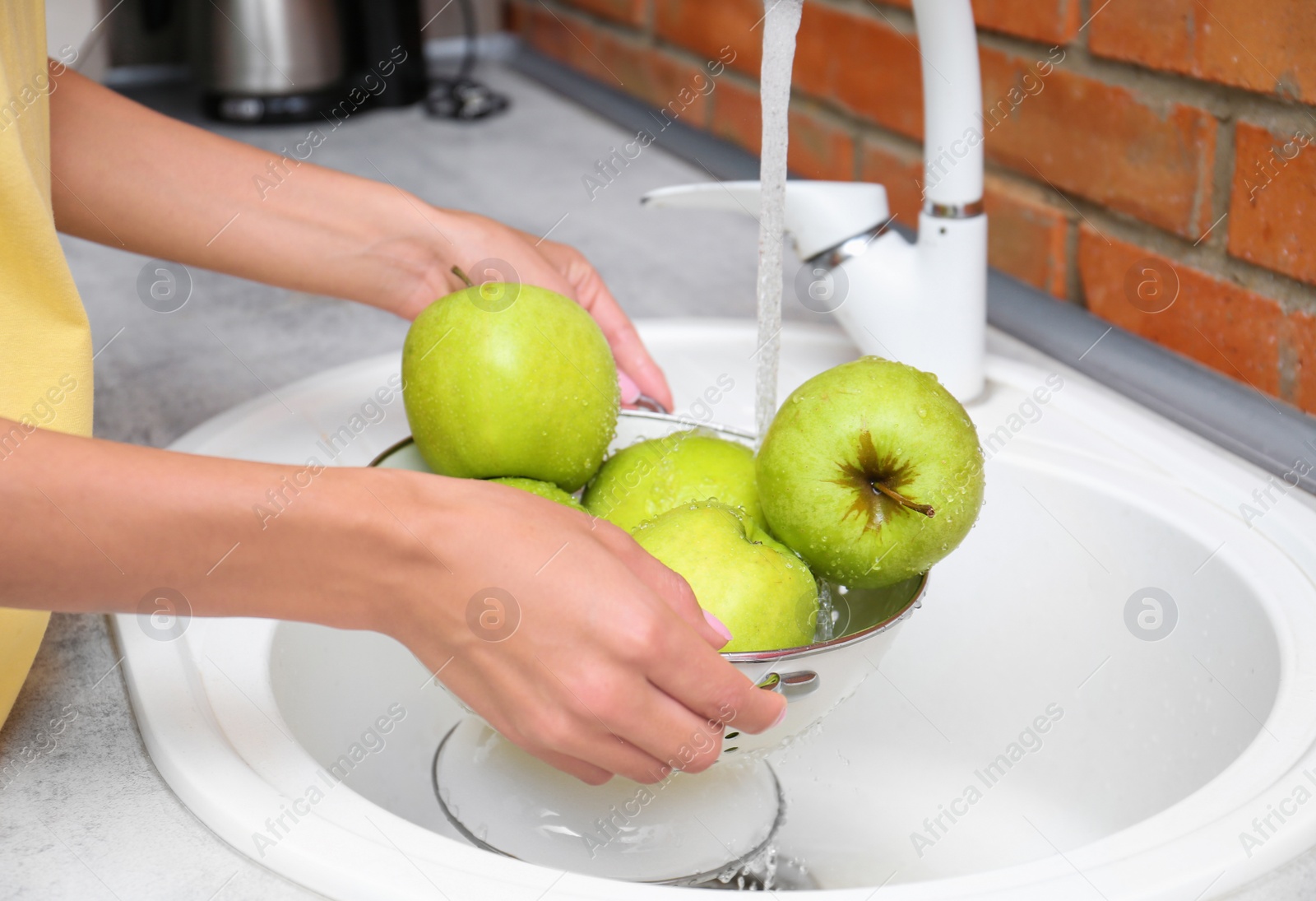 Photo of Woman washing fresh apples in kitchen sink, closeup