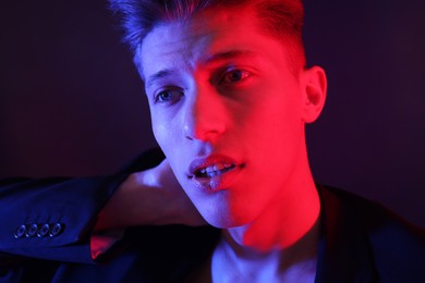 Photo of Young man on dark background in neon lights