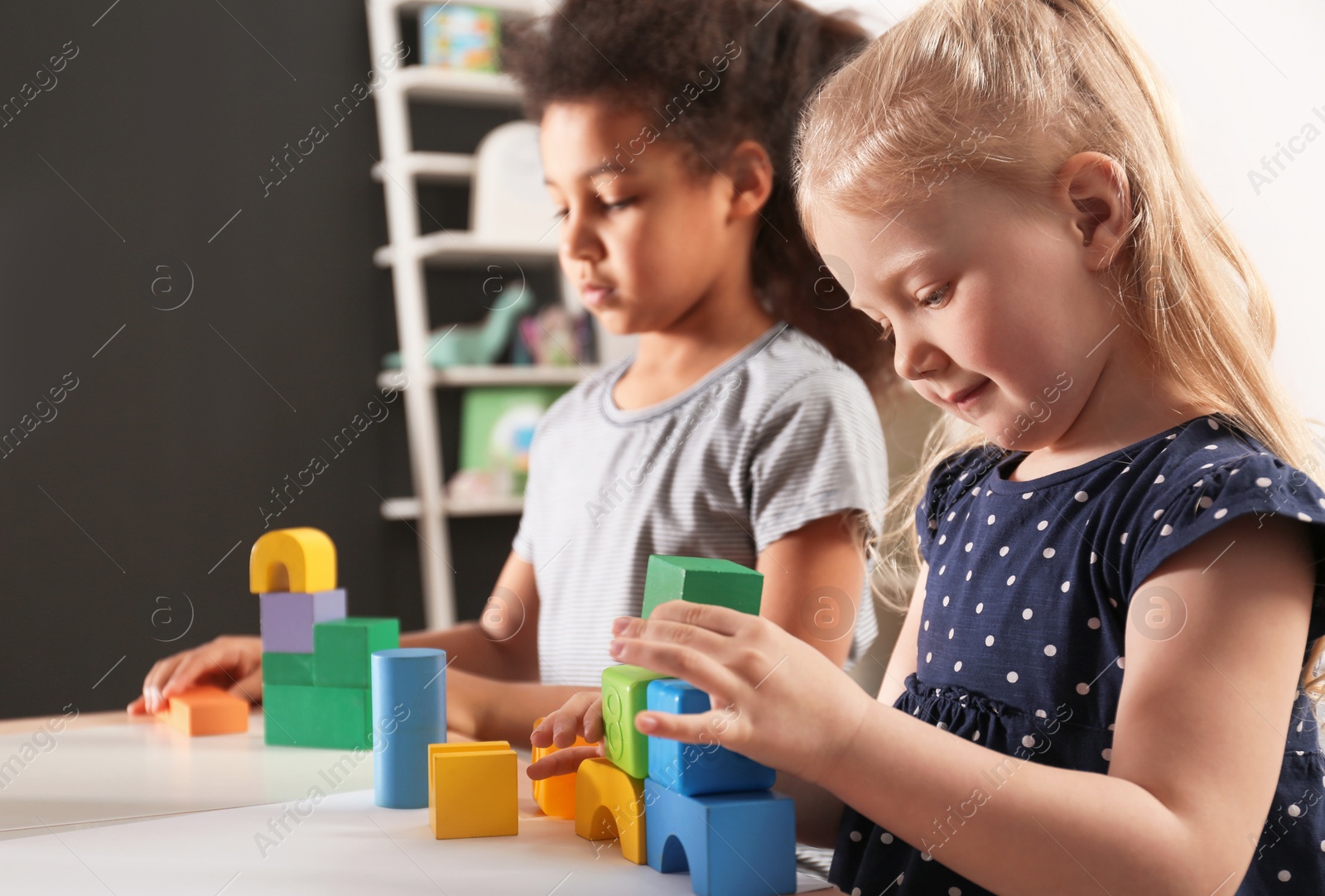 Photo of Cute little children playing with building blocks in kindergarten. Indoor activity