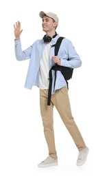 Young man with cap, headphones and backpack waving hand on white background