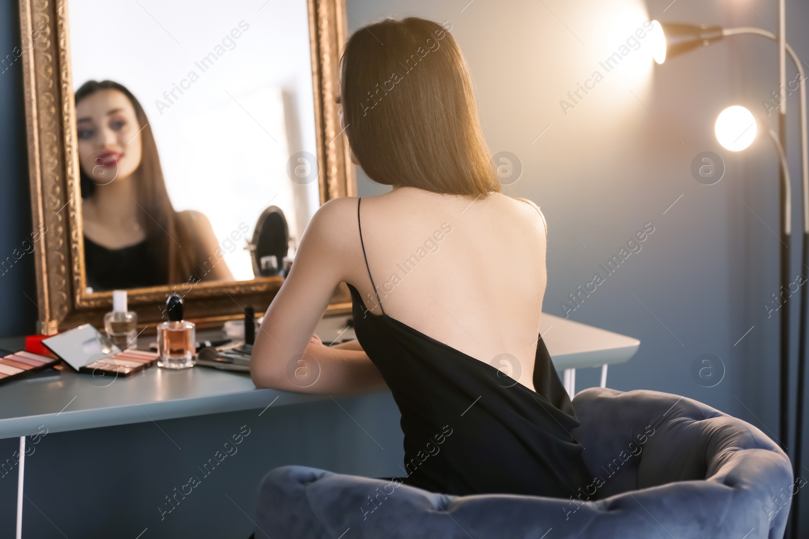 Photo of Portrait of beautiful woman with bright makeup near mirror indoors