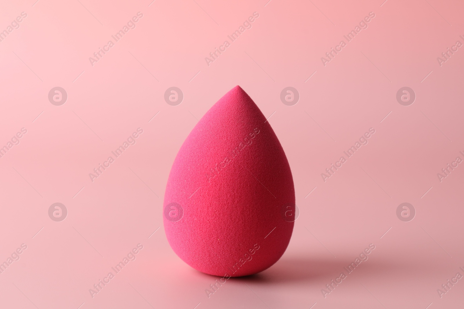 Photo of One bright makeup sponge on pink background