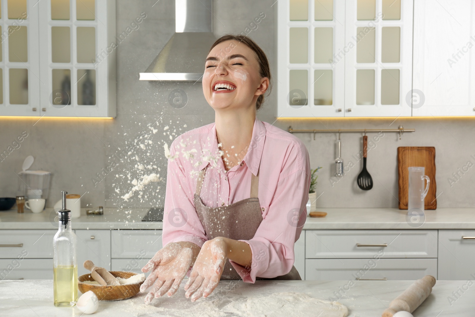 Photo of Happy woman having fun at messy table in kitchen