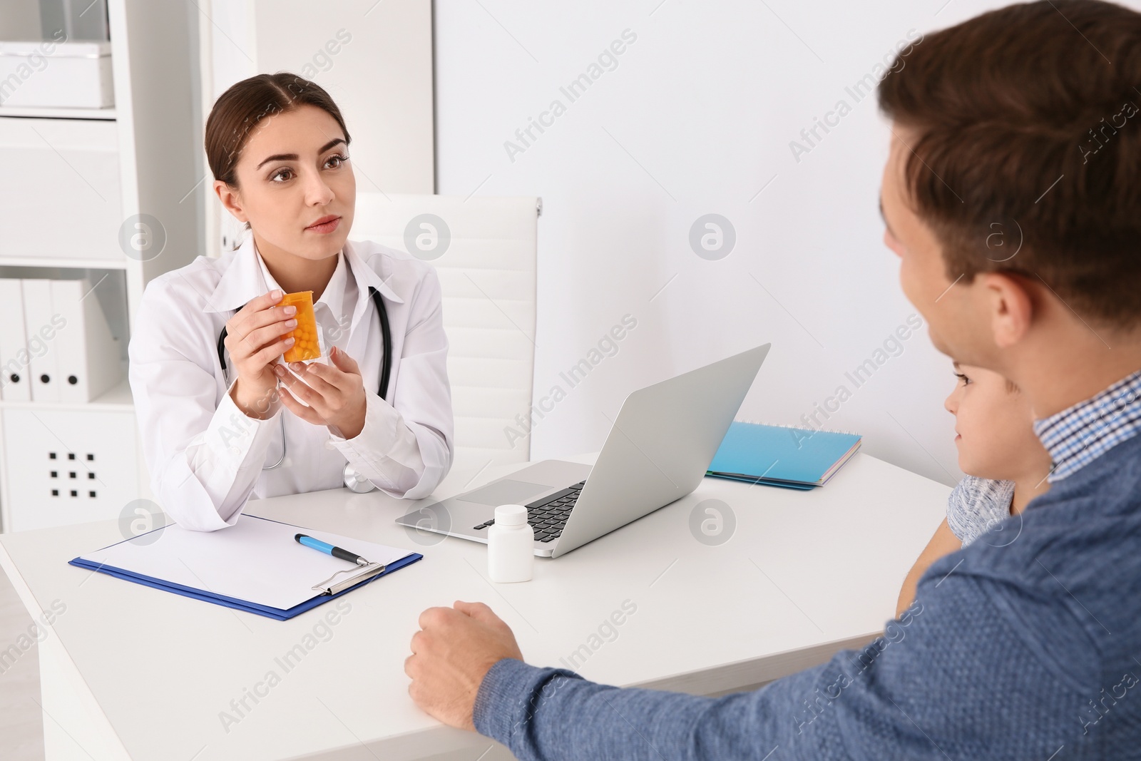 Photo of Father and son visiting pediatrician. Doctor working with patient in hospital