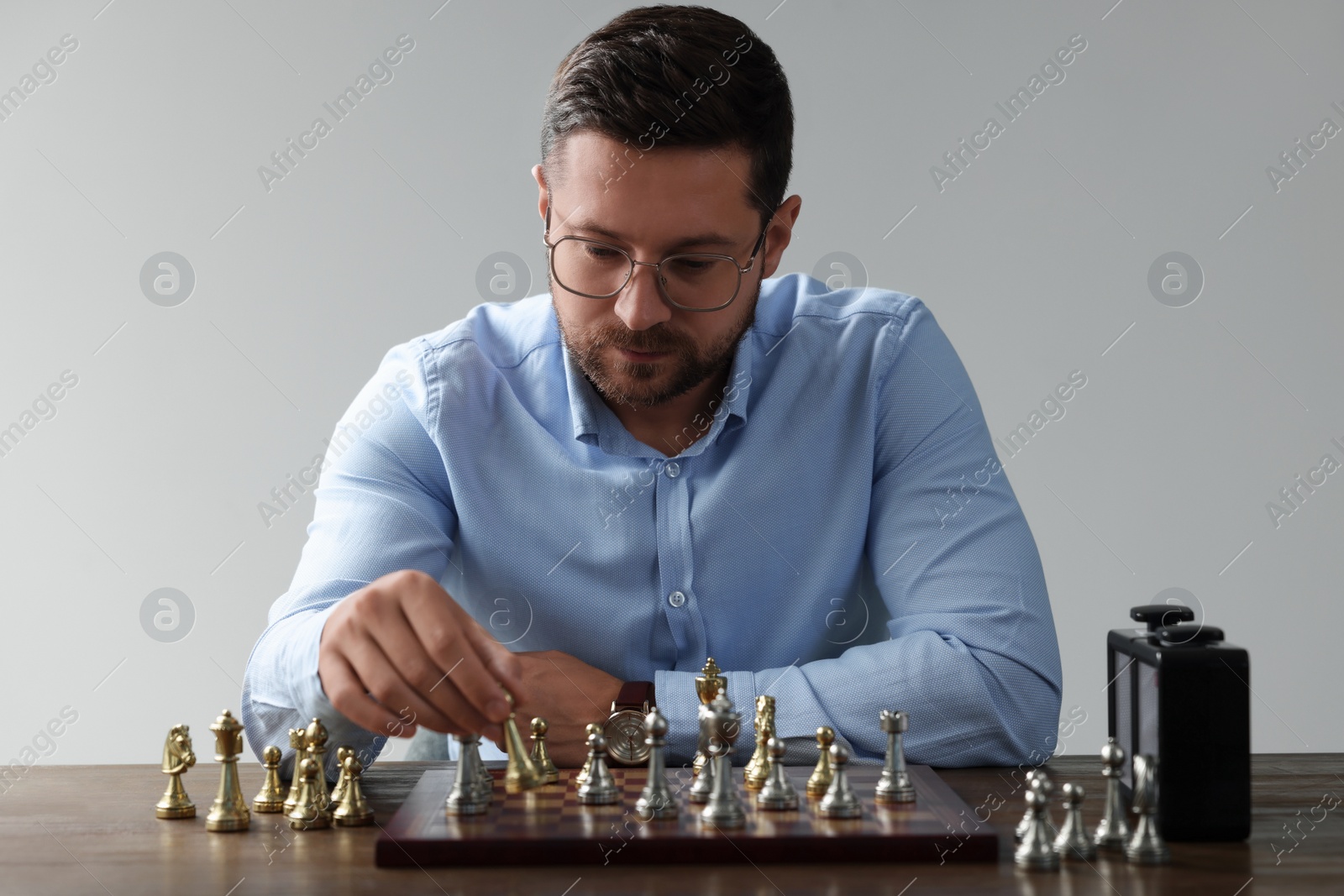 Photo of Man playing chess during tournament at table against gray background