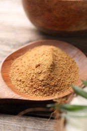 Spoon with coconut sugar on wooden table, closeup