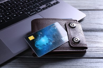 Photo of Credit card, leather wallet and laptop on grey wooden table