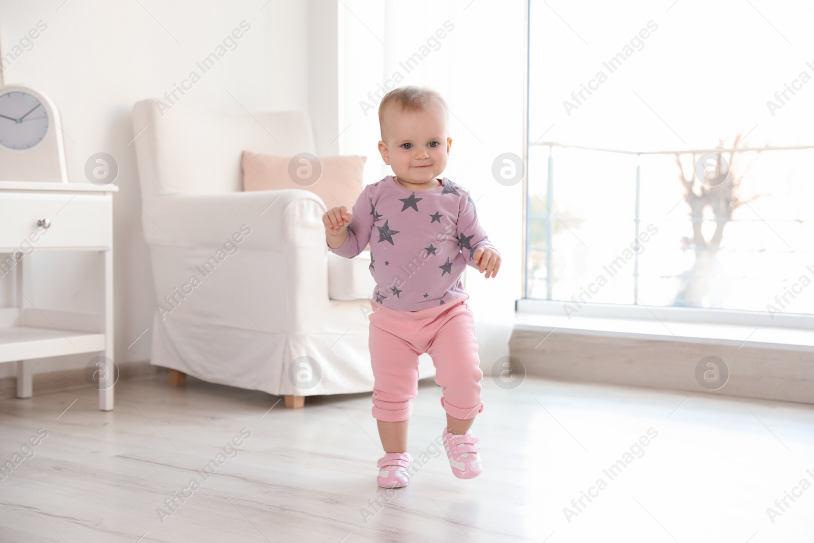 Photo of Cute baby girl walking in room at home