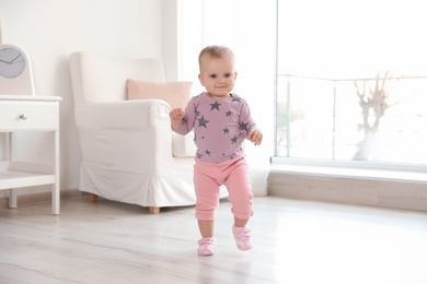 Cute baby girl walking in room at home