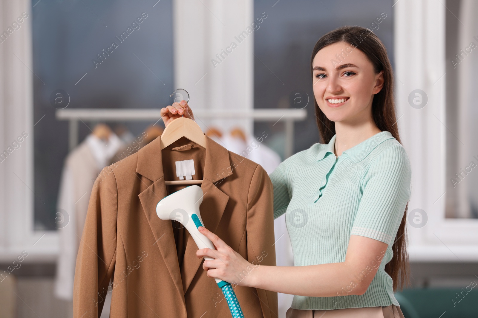 Photo of Woman steaming jacket on hanger at home