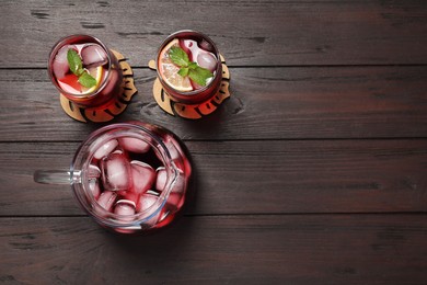 Refreshing hibiscus tea with ice cubes and mint on wooden table, flat lay. Space for text