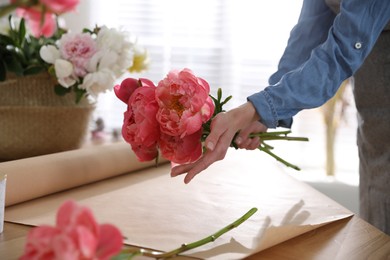 Photo of Florist making beautiful peony bouquet at table, closeup