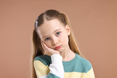 Portrait of sad girl on light brown background