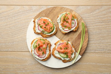 Photo of Tasty canapes with salmon served on wooden table, top view