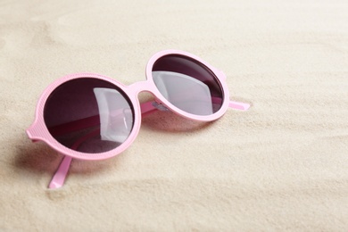 Stylish sunglasses on white sand, space for text. Summer time