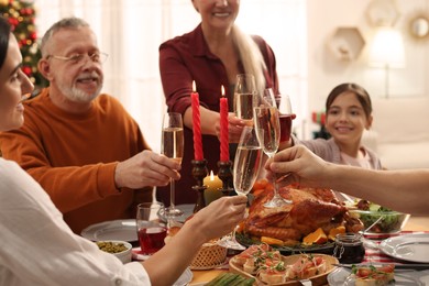Photo of Family clinking glasses of drinks at festive dinner, focus on hands. Christmas celebration