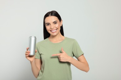 Photo of Beautiful happy woman holding beverage can on light grey background