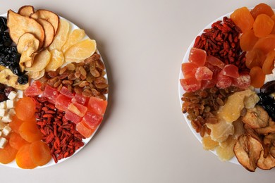 Plates with different dried fruits on white background, top view