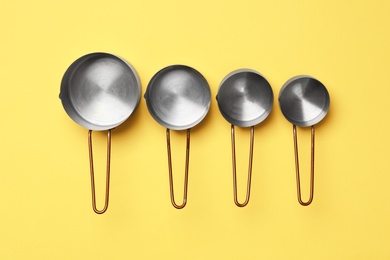 Photo of Different saucepans on yellow background, flat lay. Cooking utensils