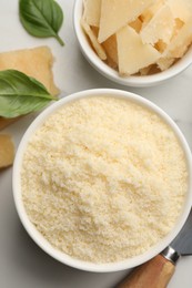 Photo of Bowl with grated parmesan cheese on white table, flat lay