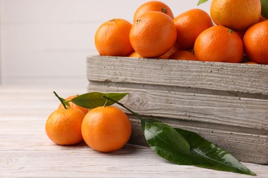 Photo of Delicious tangerines with leaves on light wooden table