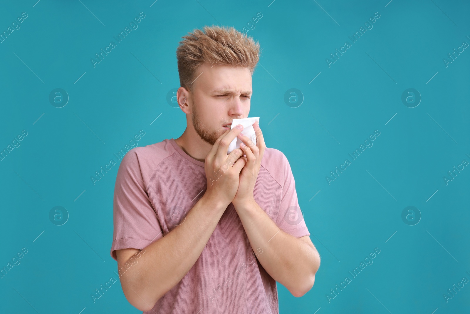 Photo of Young man suffering from allergy on blue background