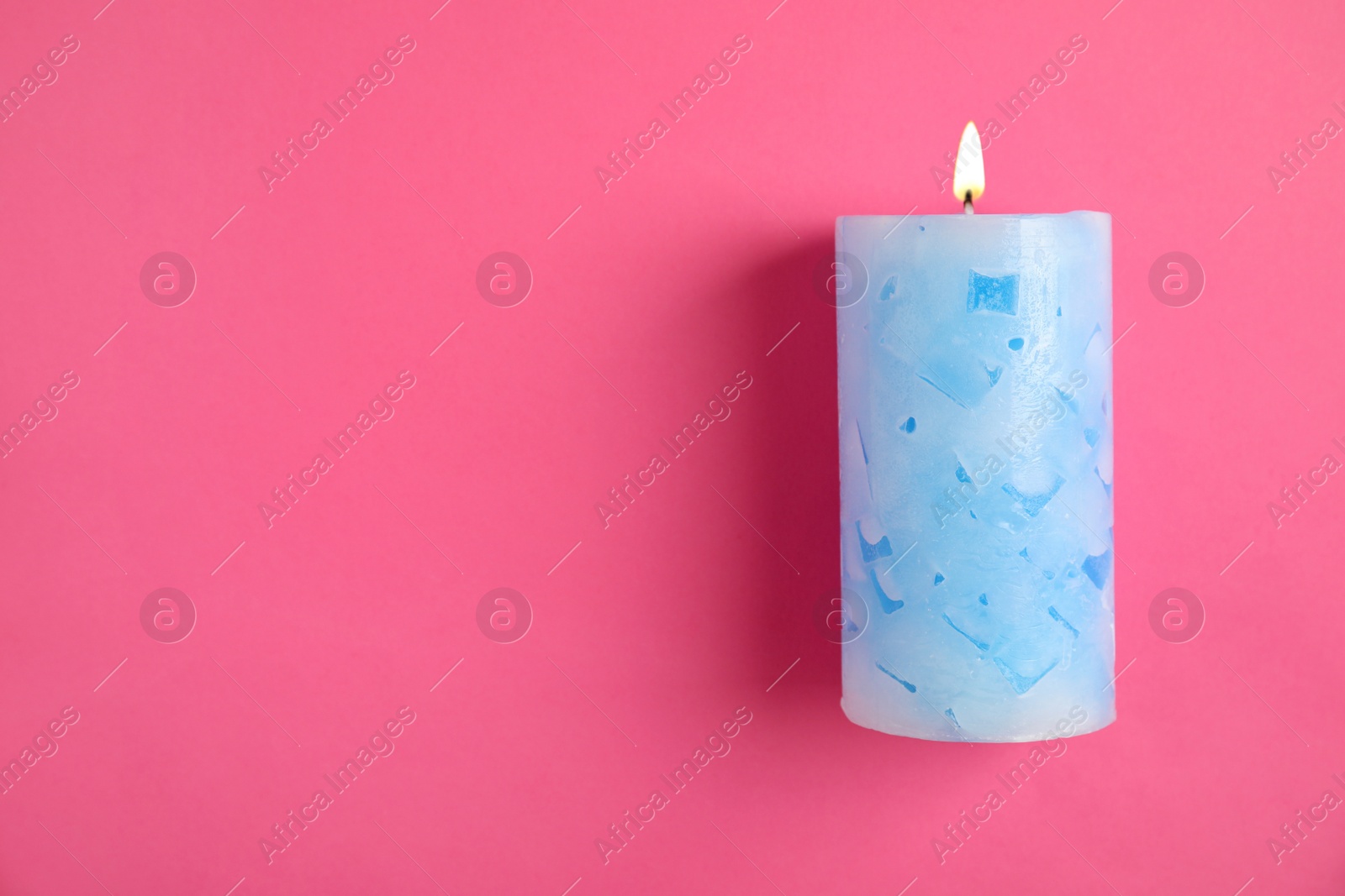 Photo of Alight wax candle and space for text on color background