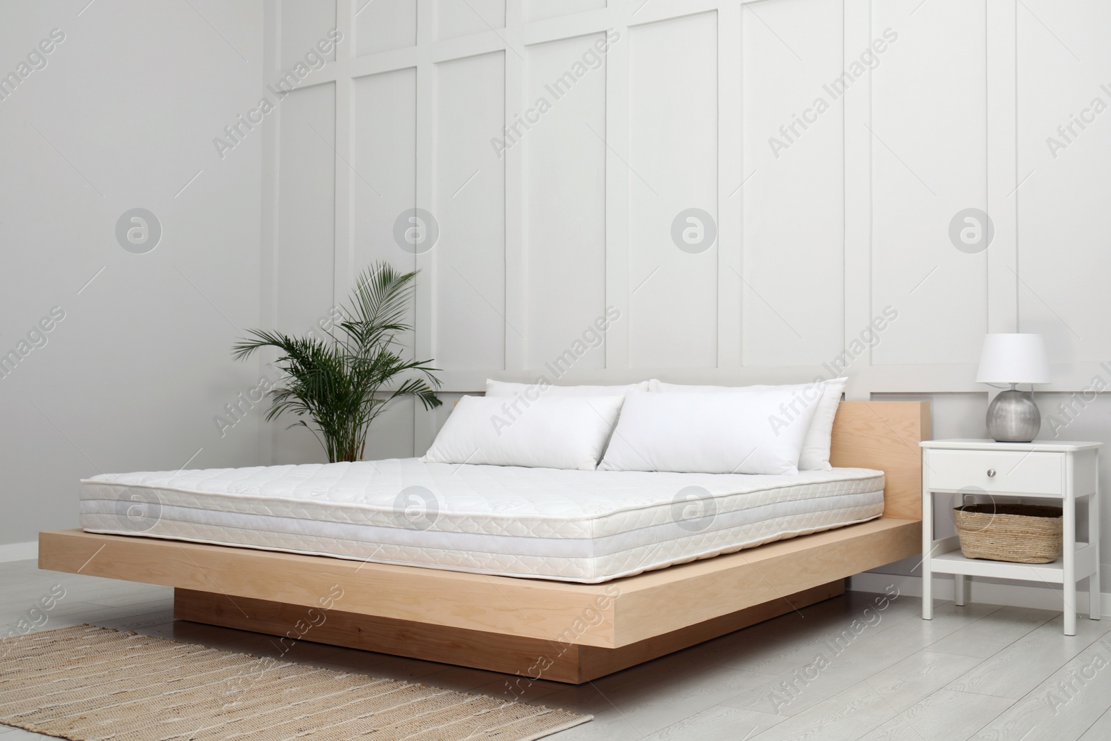 Photo of Wooden bed with soft white mattress and pillows in cozy room interior