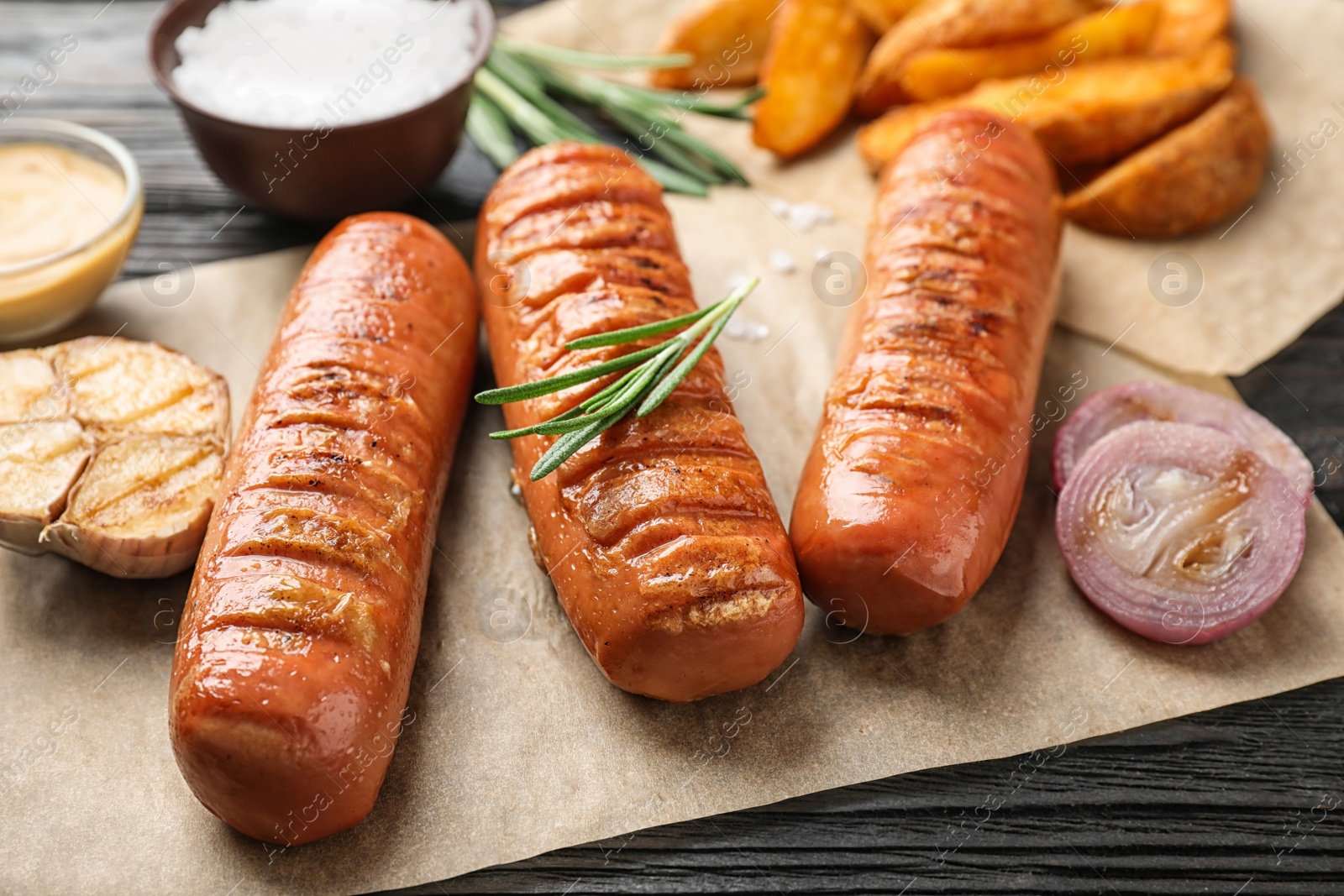 Photo of Delicious grilled sausages and vegetables on wooden table, closeup. Barbecue food